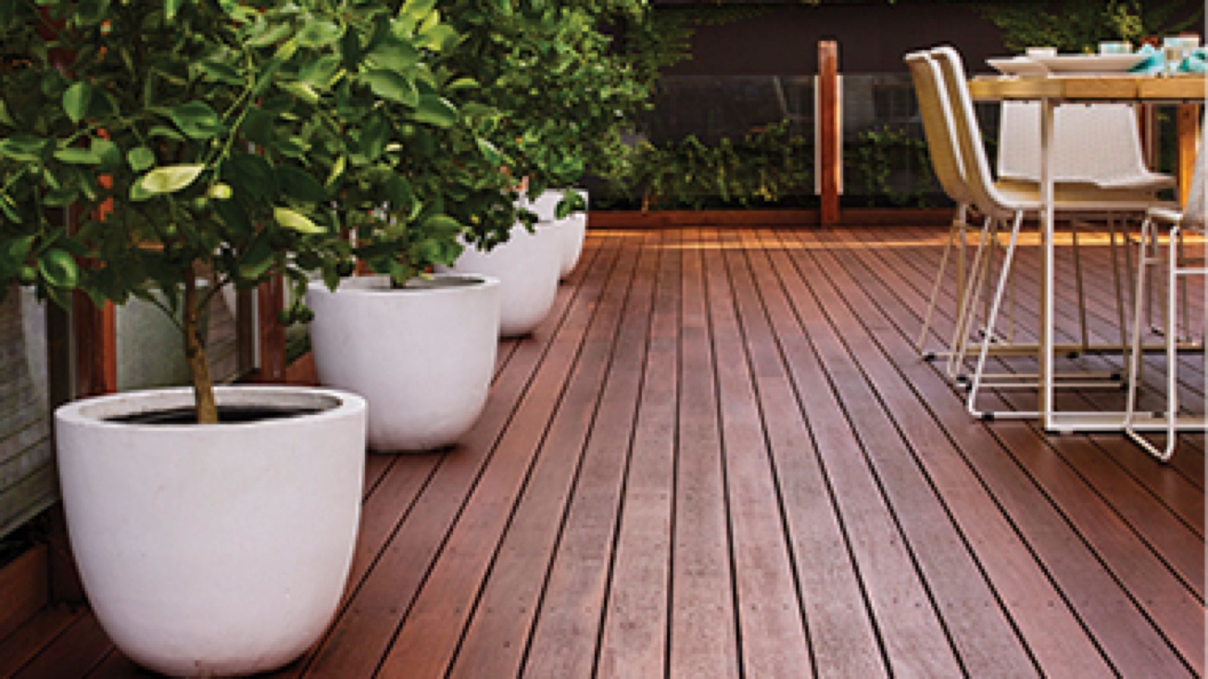 Hardwood timber deck with white planters and outdoor dining setting