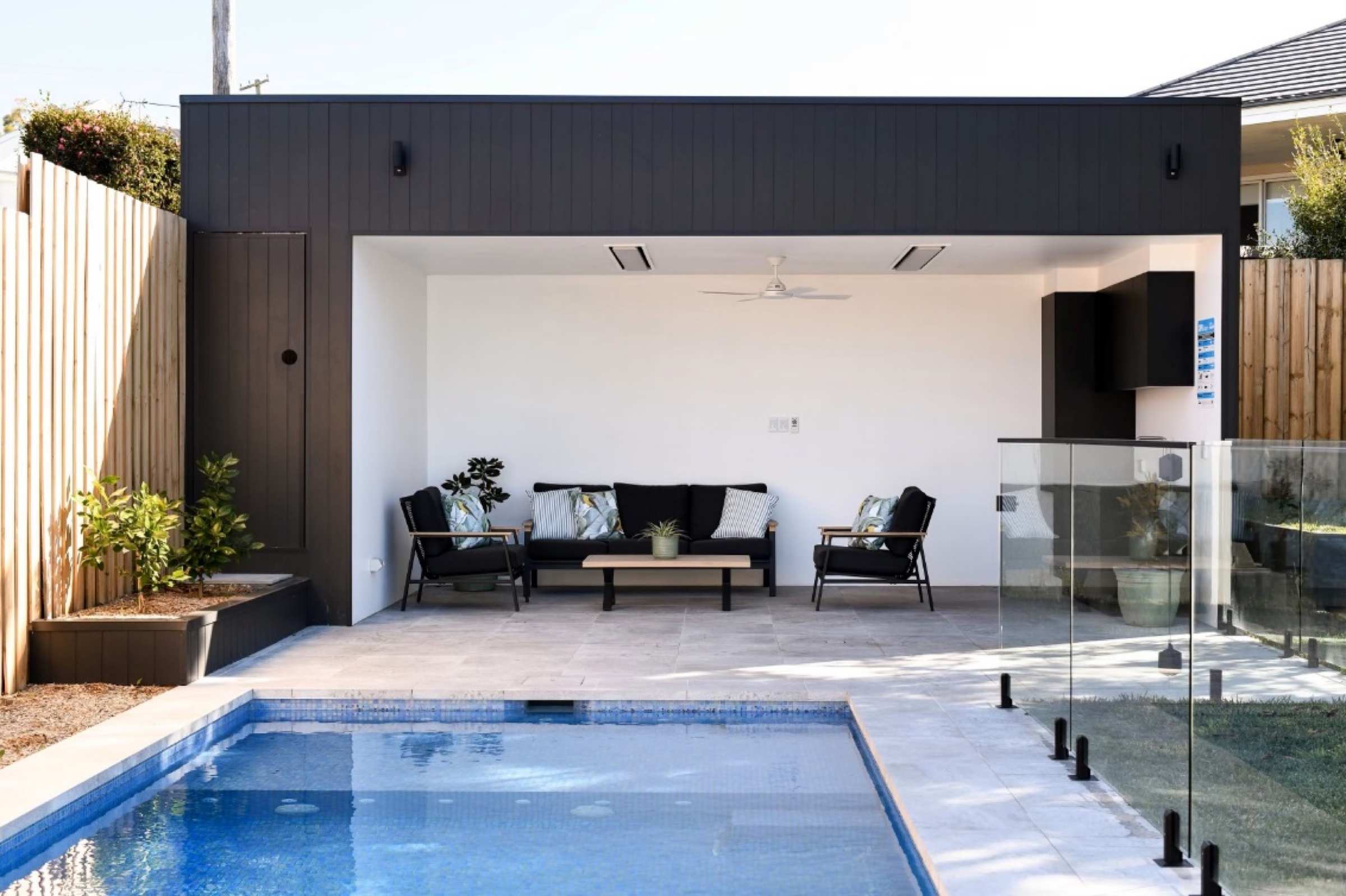 Pool cabana built by Urban Craft Constructions, with a dark clad roof over an open lounge beside the pool